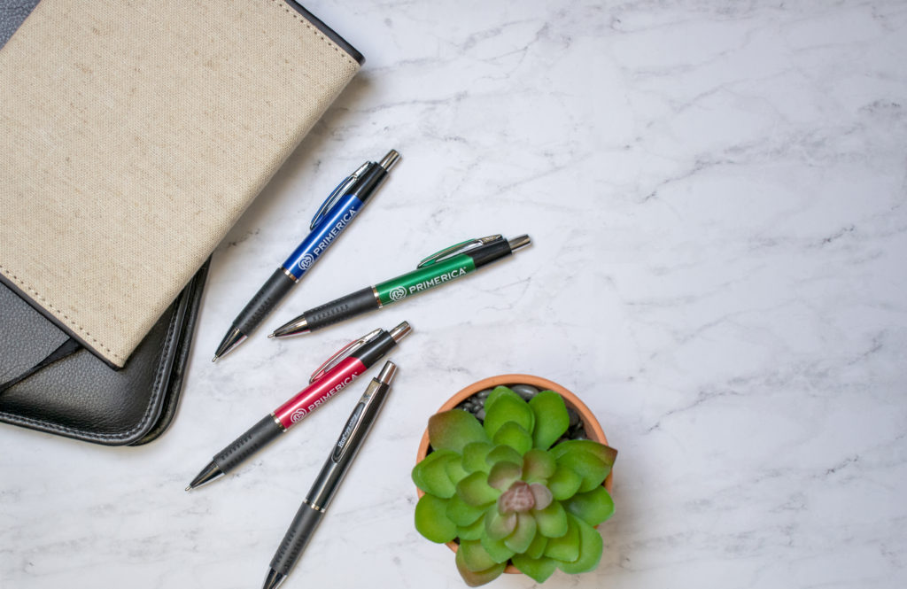 Consuelo promotional pens on a marble counter with journals